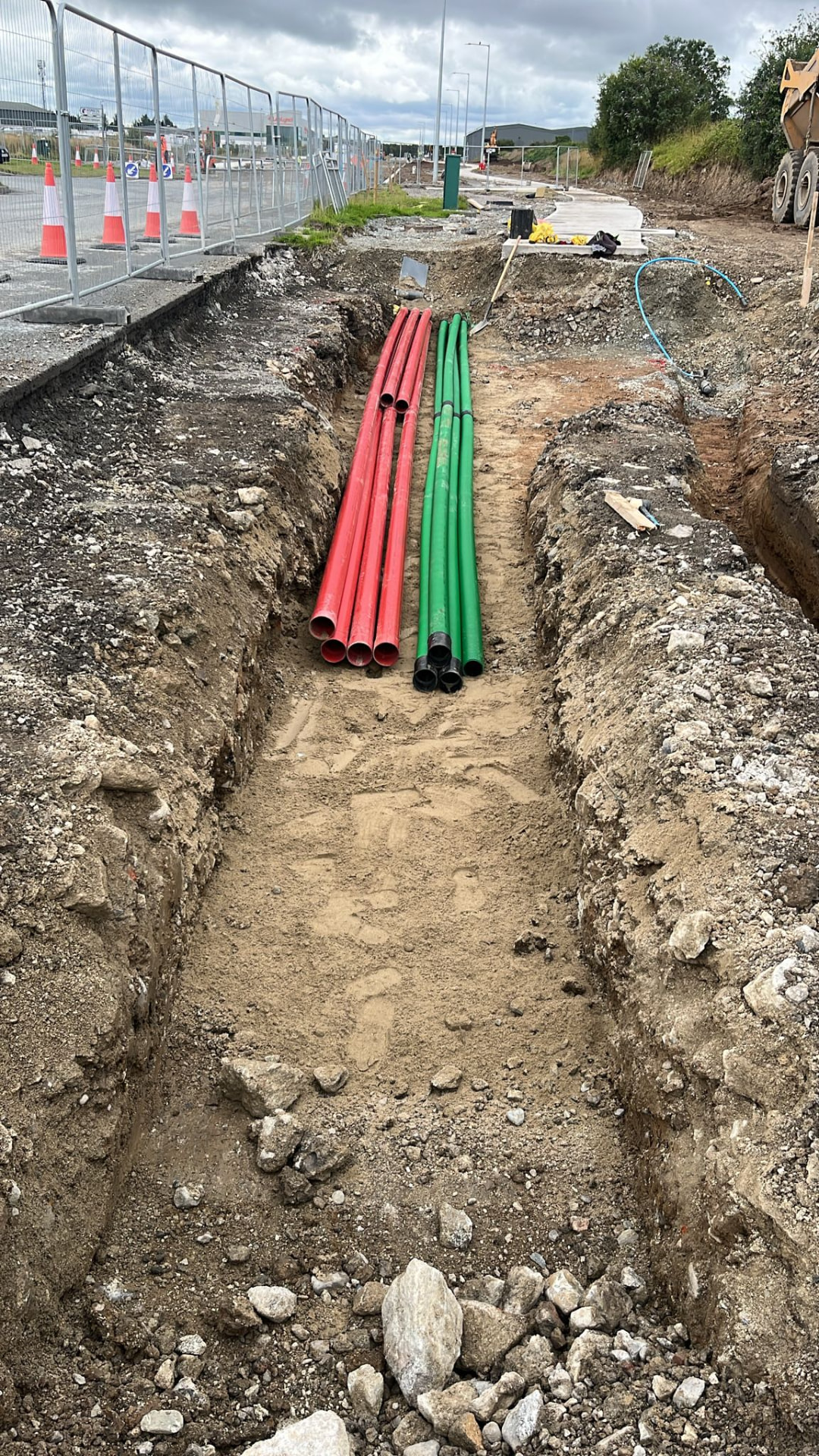 Red and green utility ducting installed in an open trench